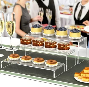 Acrylic risers with a selection of desserts, adding elegance to a catered event setup.