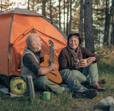 Older man and woman camping and playing guitar free from urinary incontinence worries