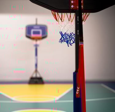 Canestro da basket nell'area multisport della palestra Move 2 Grow a Milano, con campo colorato sullo sfondo.