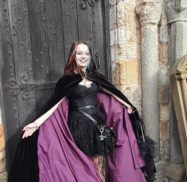 a woman in a black dress wearing a purple lined velvet cloak