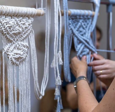 Proyecto de arte colgante de pared de macramé hecho a mano en progreso sobre un perchero de metal.