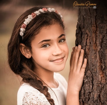 niña de comunión apoyada en un árbol