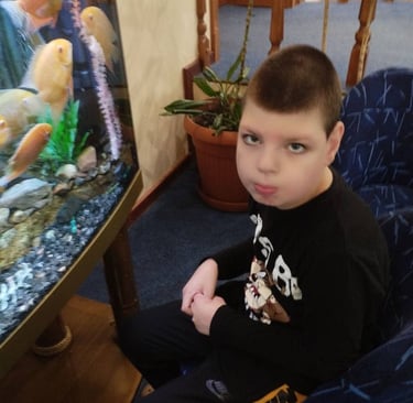молодий хлопчик сидить у кріслі з акваріумом