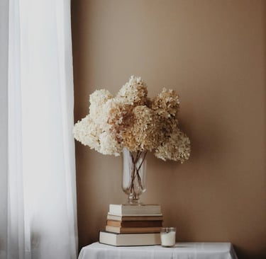 Vase de fleurs séchées sur des livres, symbole d’un espace calme, doux et conscient de ressourcement