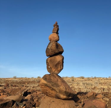 stacked stones on dry land against blue sky