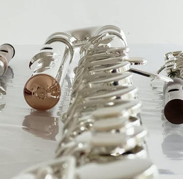 une flûte traversière en or, un piccolo en bois et une flûte en sol en argent, posées côte à côte