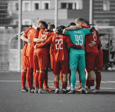 a group of soccer players huddle around a soccer field