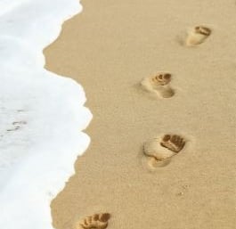 empreintes de pas sur le sable au bord de l’océan symbolisant le chemin en sophrologie humaniste