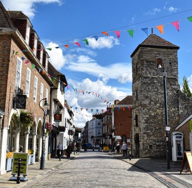 Rue pavée ensoleillée avec des batiments en briques rouges et des drapeaux colorés