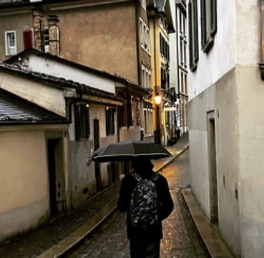 A person walks through narrow alleys holding their umbrella in rainy Switzerland photography by LV