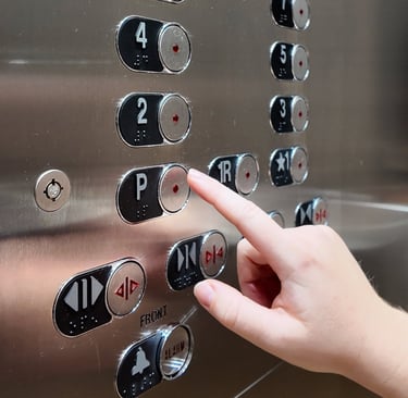 a hand with outstretched finger about to press the floor button on an elevator control panel