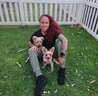 a woman sitting on the grass with two dogs