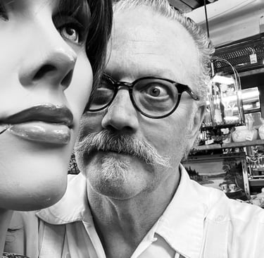 Dan Self, a man with a mustache and glasses looking at a mannequin