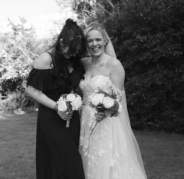 bridesmaid and bride laughing with each other holding bouquet