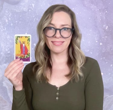 Natalie Grace, founder of Crystal aura Tarot, holding The Magician Card with amethyst background