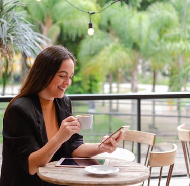 uma mulher sentada a uma mesa com uma xícara de café