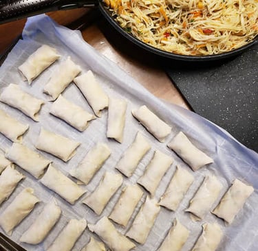 uncooked Thai spring rolls ready for freezing on parchment paper on a cookie sheet