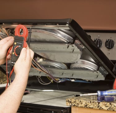 a man in a blue shirt is fixing a stove top