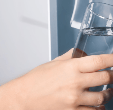 a person holding a glass of water in front of a refrigerator