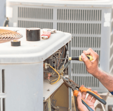 a man in a blue shirt is working on a large air conditioner