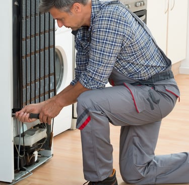 a man in a plaid shirt and pants is fixing a dishwasher