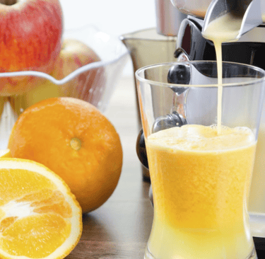 a juicer with orange juice being poured into a glass