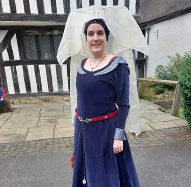 a woman in a medieval costume standing in front of a house