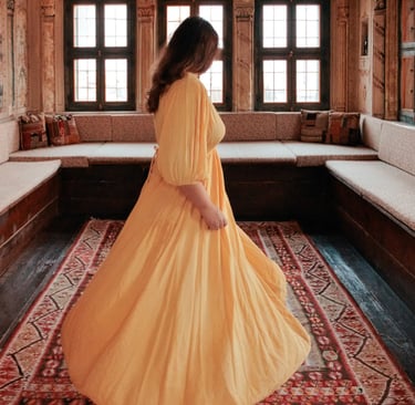 Woman in a yellow dress standing in an ornate Ottoman-style room in Cappadocia