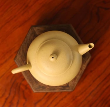 Overhead view of a light yellow teapot placed on a wooden stand