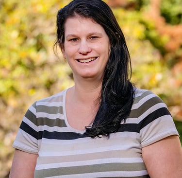 Image of Michelle smiling against background of yellow fall leaves