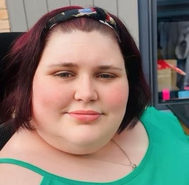 Katie in a green top sitting outside with hair in headband