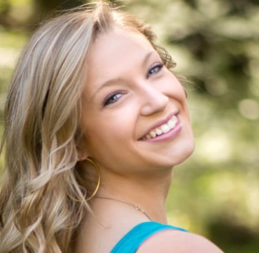 a woman in blue dress smiling and looking at the camera