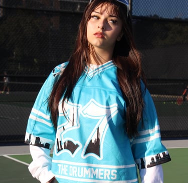 a woman in a blue shirt and jeans standing on a tennis court