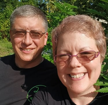 a man and woman sitting in front of a hemp plant