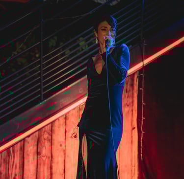 Jessie BaréKa interprète une chanson sur scène en robe noire élégante.