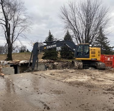John Deere excavator digging up home from demolition project