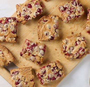squares of cut cranberry cake on a wood board
