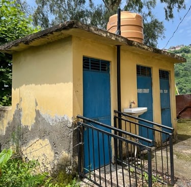 Small yellow toilet block with 3 blue doors.