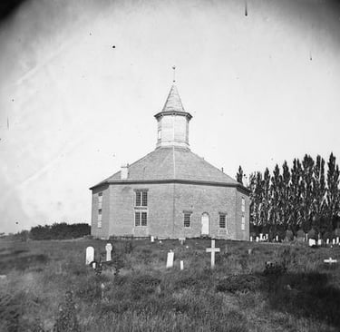 An octagonal church building with a graveyard in black and white
