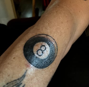 a tattooed arm with a black and white 8-ball tattoo