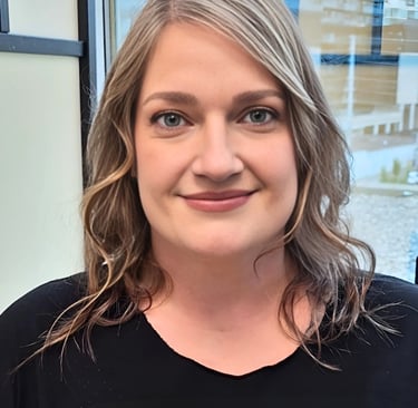 Professional portrait of a smiling woman with wavy blonde hair wearing a black shirt.