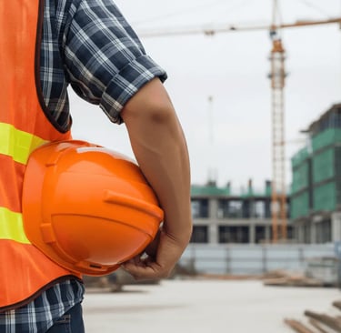 Pessoa segurando capacete de obra laranja
