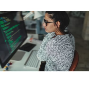 a woman sitting at a desk with a laptop and a laptop