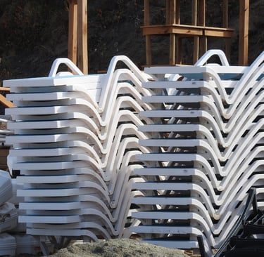 a pile of plastic chaise lounges chairs with plastic chairs