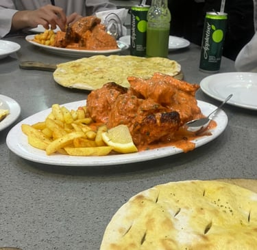 a table with peri-peri chicken, fries, naan, and drinks