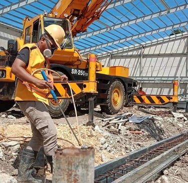 exterminator in safety gear near a yellow mobile crane at a steel frame building site.
