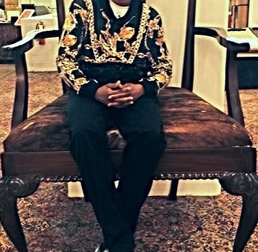 CEO Nathaniel Banks sitting on an oversized vintage throne chair wearing a designer gold chain print hoodie.