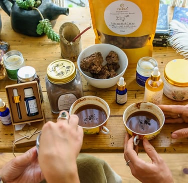 A wooden table with ceremonial cacao, medicinal mushroom supplements, and essential oils for holistic wellness.
