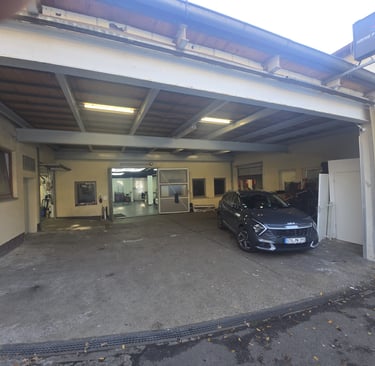 Eingangsbereich der KFZ-Werkstatt mit einem geparkten Auto, bereit für Reparatur oder Service.