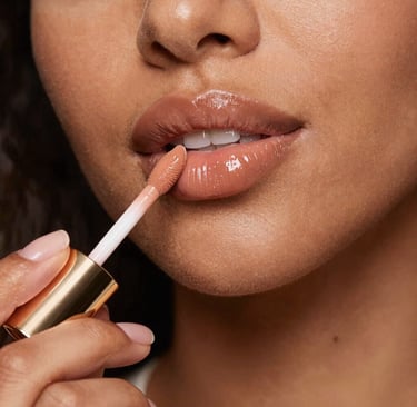 Close-up of a shiny, soft pink lip gloss tube with a subtle shimmer.